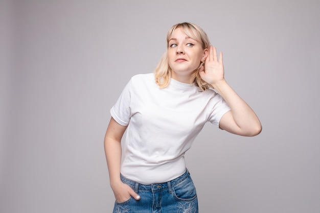 Photo charmante fille écoutant des potins. portrait en studio de beau caucasien