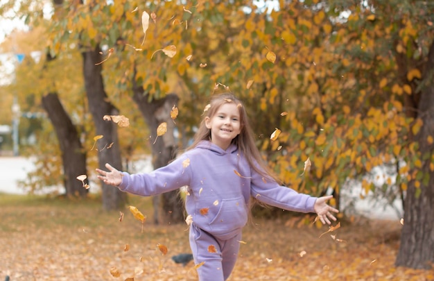 Charmante fille heureuse jette des feuilles mortes tout en jouant dans un parc d'automne et rit par une journée ensoleillée Ressentir la paix intérieure bonheur harmonie Mise au point sélective