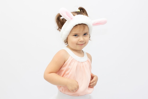 Charmante fille en robe et oreilles blanches se faisant passer pour un lapin mignon sur fond gris