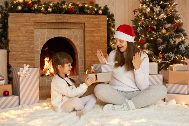 Charmante gamine présentant un cadeau de Noël à sa mère le matin de Noël