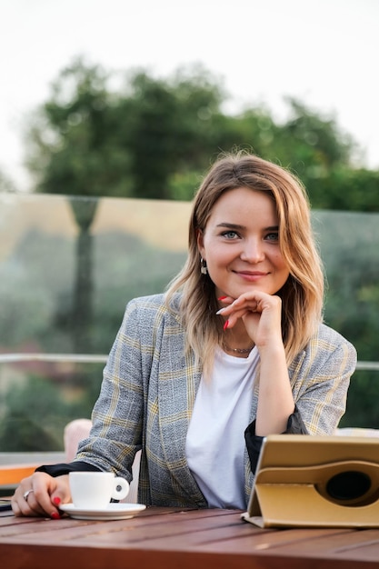 Charmante jeune femme d'affaires assise à la table avec tablette