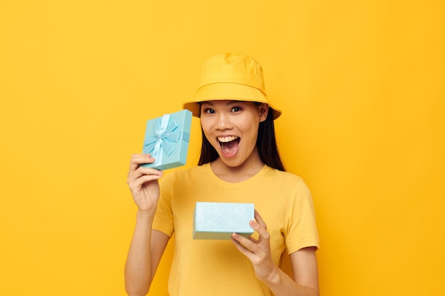 Charmante jeune femme asiatique dans un t-shirt jaune et un chapeau avec un fond jaune cadeau inchangé