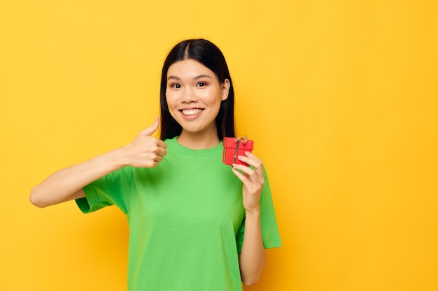 Charmante jeune femme asiatique avec une petite boîte cadeau vacances fond isolé inchangé