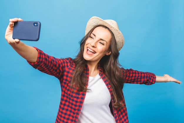 Charmante jeune femme au chapeau blanc voyage et prendre selfie