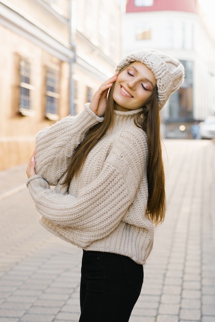 Charmante jeune femme aux cheveux bruns en promenade. Une femme belle et heureuse dans une image élégante dans un chapeau chaud tricoté. Se promener dans la ville, style de vie