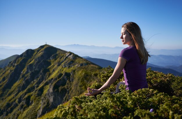 Charmante jeune femme méditant dans les montagnes
