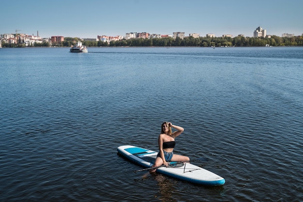 Charmante jeune femme sur paddle board SUPat le lac de la ville, vacances à l'heure d'été