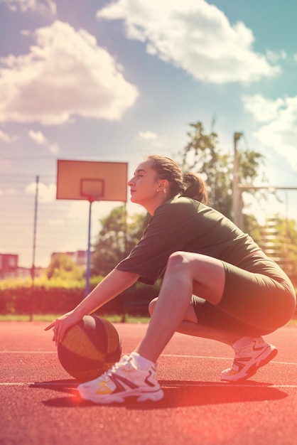 Une charmante jeune femme porte un tissu de sport avec un ballon de basket se repose après une journée d'été active pour le sport