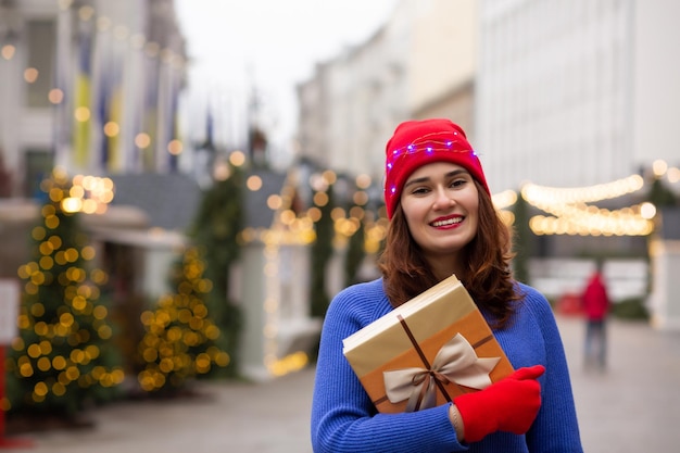 Charmante jeune femme recevant un cadeau dans une boîte à la foire de Noël. Espace pour le texte