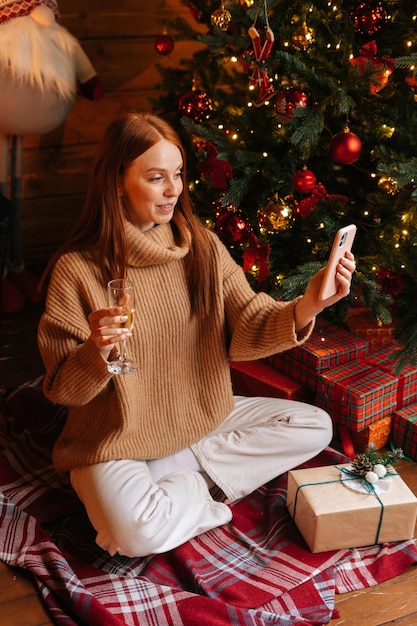 Charmante jeune femme rousse félicitant et portant un toast tenant une coupe de champagne