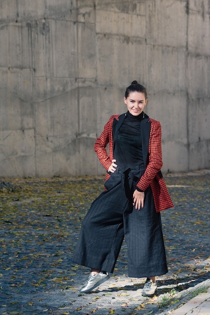 charmante jeune femme souriante dans des vêtements à la mode Chemisier noir et pantalon tuile veste à carreaux rouge