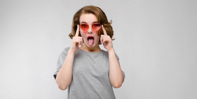 Charmante jeune femme en t-shirt gris. Femme heureuse à lunettes rouges.