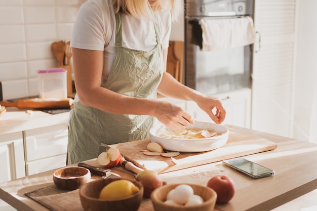 Charmante jeune femme en tablier de chef préparant une tarte à la maison dans la cuisine Intérieur de maison confortable