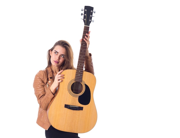 Charmante jeune femme en veste marron tenant une guitare sur fond blanc en studio