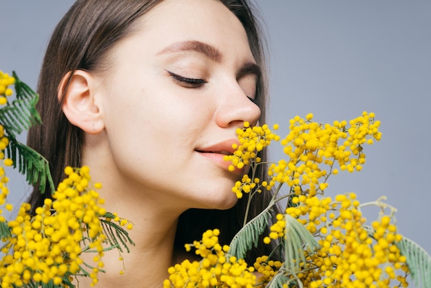 Charmante jeune fille appréciant le parfum du mimosa jaune