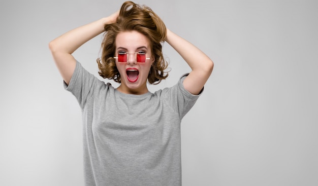 Charmante jeune fille dans un t-shirt gris sur fond gris