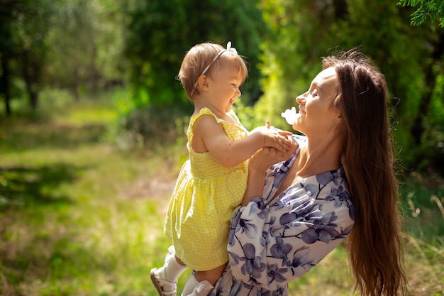 Charmante jeune maman s'amusant avec sa petite fille au jardin