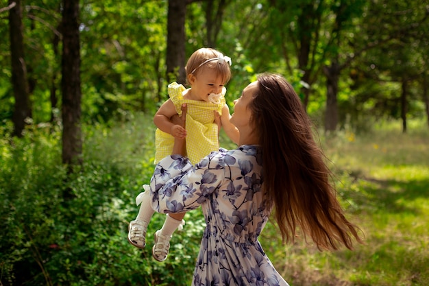 Charmante jeune maman s'amusant avec sa petite fille au jardin