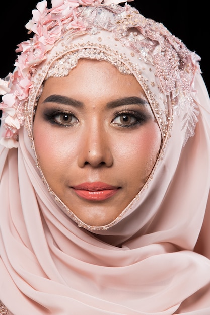 Charmante mariée arabe musulmane asiatique en dentelle perlée broderie rose douce robe de mariée rose ancienne et foulard hijab, gros plan sur Fashion Make up Eyes Face, éclairage de studio fond noir isolé.