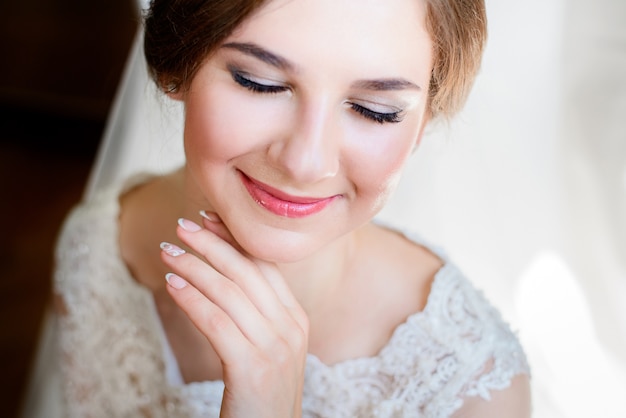 Charmante mariée avec des lèvres roses doux tient ses doigts sous le menton