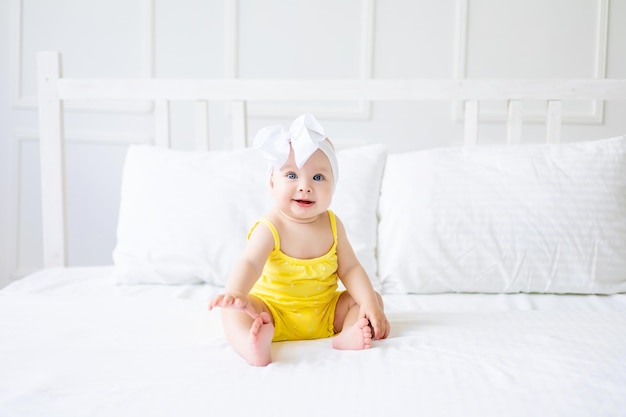 Charmante petite fille dans une chambre blanche ensoleillée Un nouveau-né se repose dans son lit Textiles et literie pour enfants Matinée familiale à la maison Un nouveau-né est assis sur le lit après avoir dormi