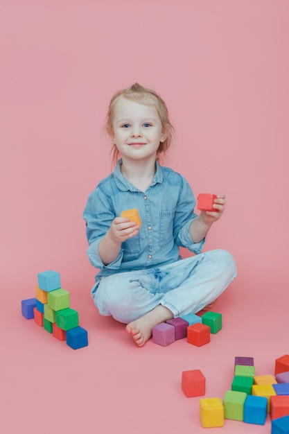 Une charmante petite fille en jean sur rose