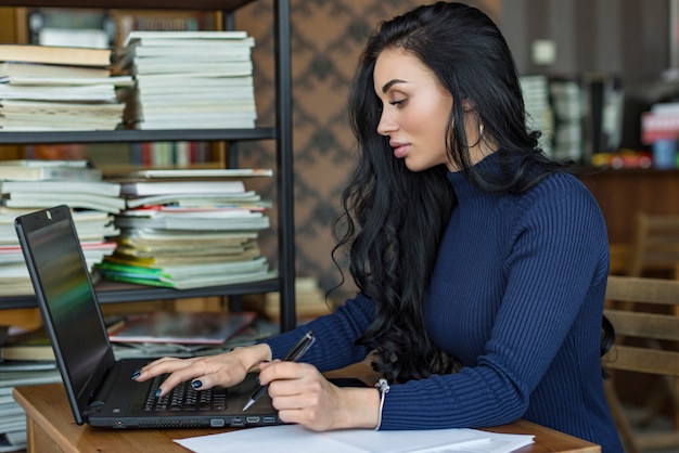 Charmantes étudiantes drôles à faire leurs devoirs assis dans la bibliothèque du collège.