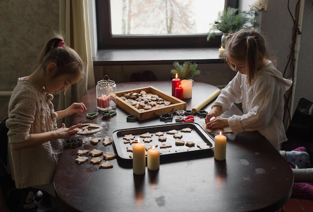 De charmantes filles cuisinent des biscuits de Noël ensemble à la maison à table