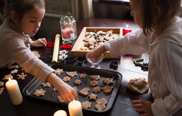 De charmantes filles cuisinent des biscuits de Noël ensemble à la maison à table