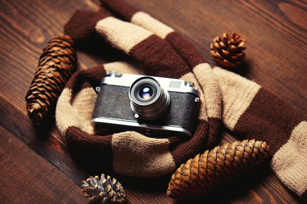 Écharpe, pommes de pin et appareil photo vintage sur table en bois