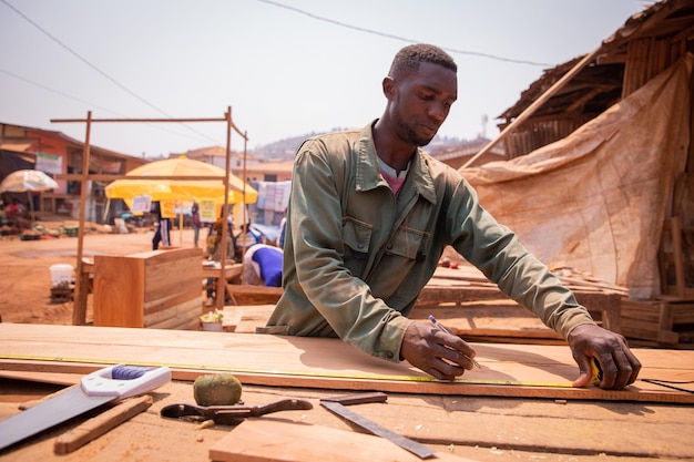 Un charpentier africain prenant des mesures tout en fabriquant un meuble