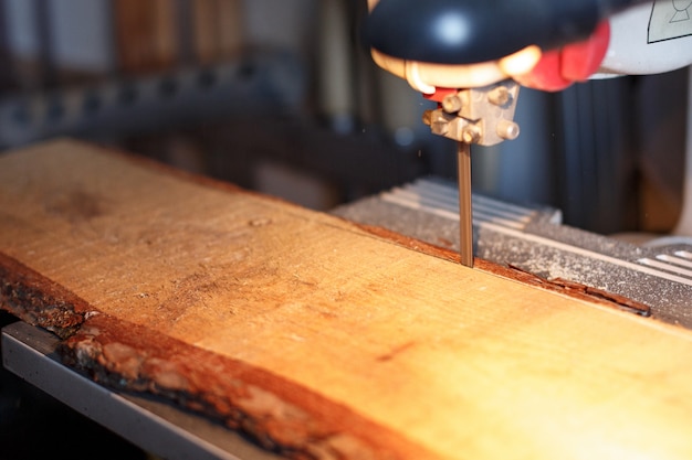 Charpentier coupant un morceau de bois avec une scie à ruban en atelier