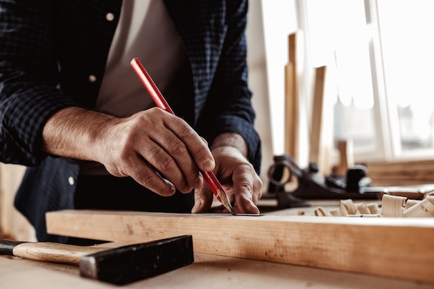 Le charpentier fait des marques de crayon sur une planche en bois