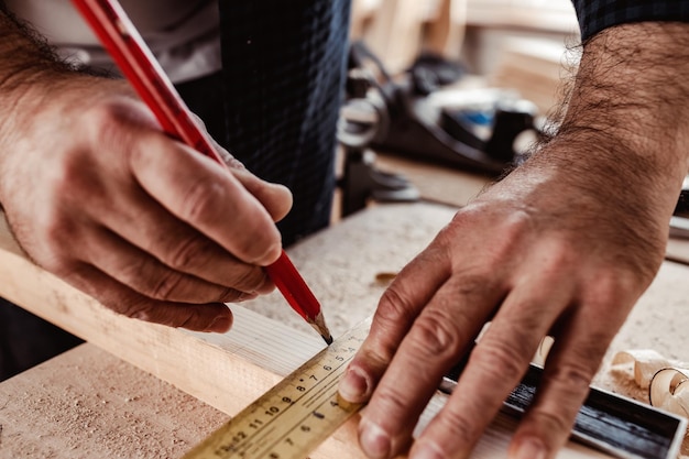 Le charpentier fait des marques de crayon sur une planche en bois