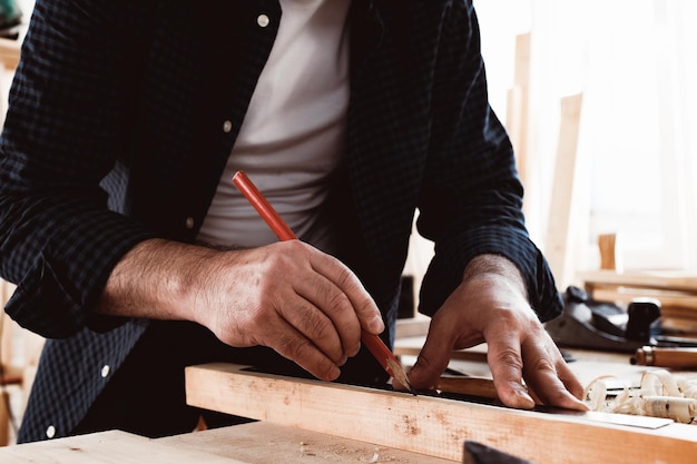 Le charpentier fait des marques de crayon sur une planche en bois