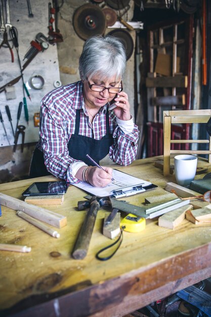 Charpentier féminin supérieur parlant au téléphone dans son atelier