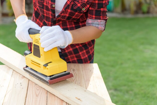 Photo charpentier femme travaillant avec une ponceuse électrique en bois