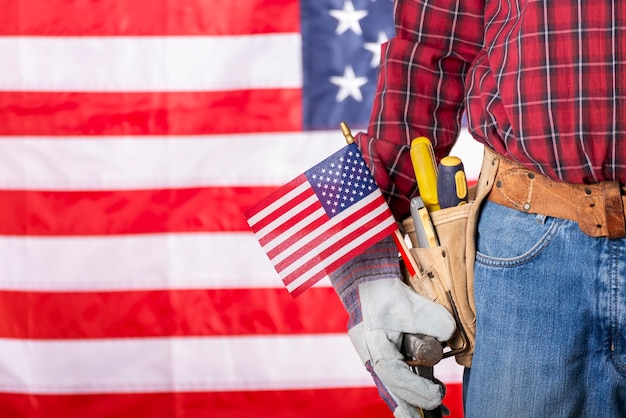 Photo charpentier en gants de protection et ceinture à outils avec drapeau américain sur fond de fête du travail