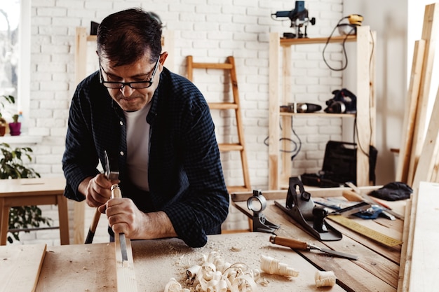 Charpentier homme d'âge moyen travaillant dans un atelier avec burin et marteau