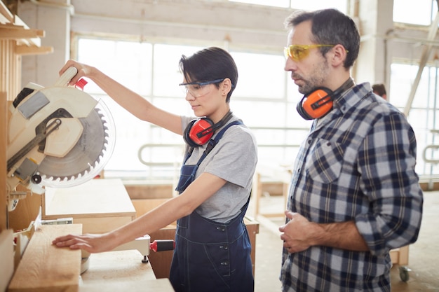 Charpentier mature aidant un stagiaire en atelier