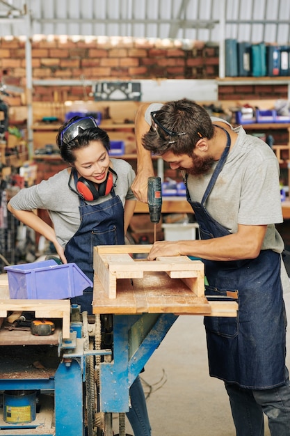 Charpentier montrant une apprentie comment assembler un tiroir en bois