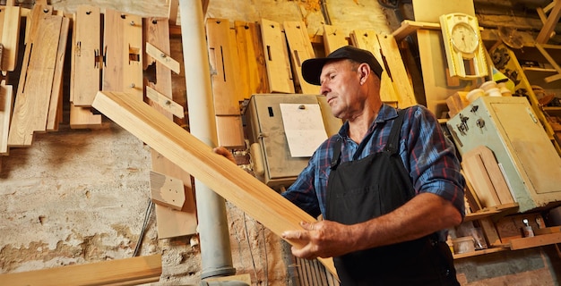 Charpentier principal en uniforme travaille avec un bois sur une machine à bois à la fabrication de menuiserie