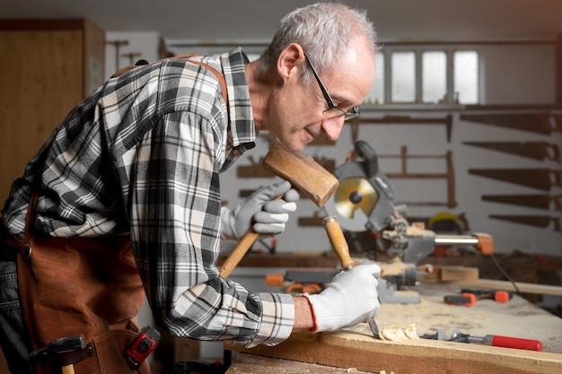 Charpentier qualifié découpant du bois avec un marteau et un ciseau Photographie de haute qualité