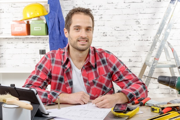 Charpentier souriant assis au bureau dans son atelier