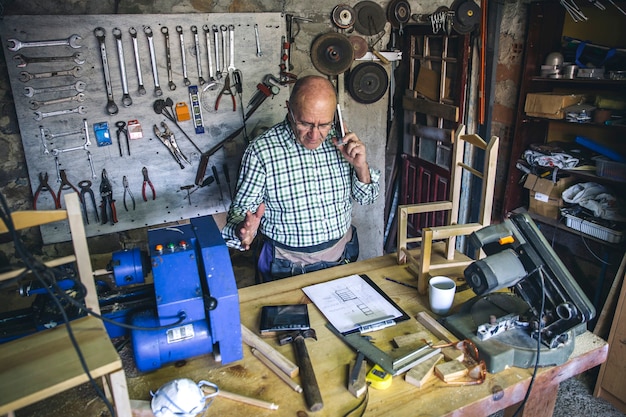 Charpentier supérieur parlant au téléphone dans son atelier