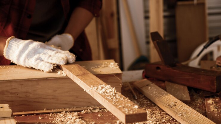 Photo charpentier tenant des morceaux de planche sur le site.