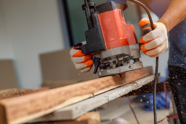 Charpentier traitant des pièces de meubles avec polisseuse. Grinder à bord