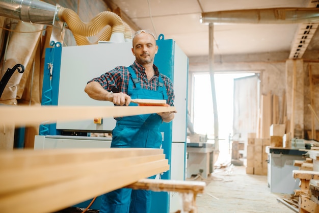 Le charpentier traite le panneau sur la machine d'avion, le travail du bois, l'industrie du bois, la menuiserie.