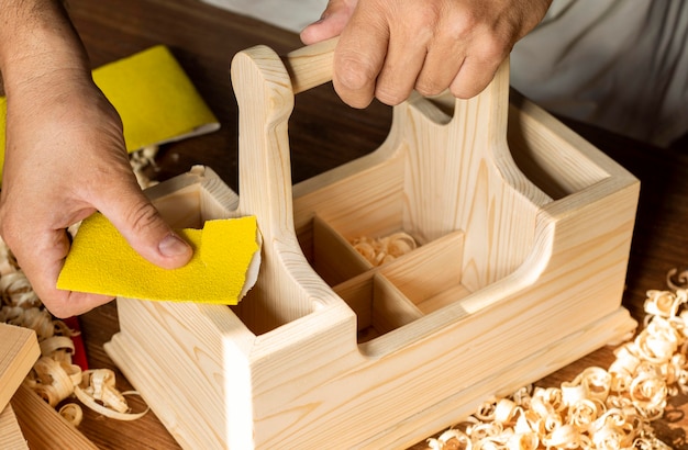 Photo charpentier travaillant avec du papier de verre jaune sur boîte en bois