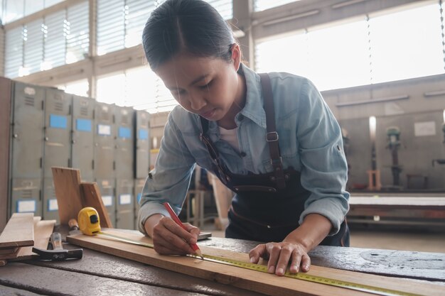 Charpentier travaillant avec de l'équipement sur une table en bois dans un atelier de menuiserie. femme travaille dans un atelier de menuiserie.